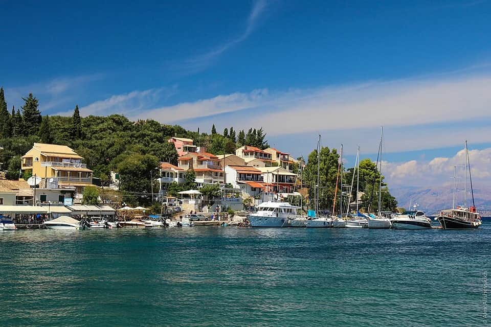 Kassiopi harbor in northern Corfu with fishing boats and waterfront restaurants along the quay